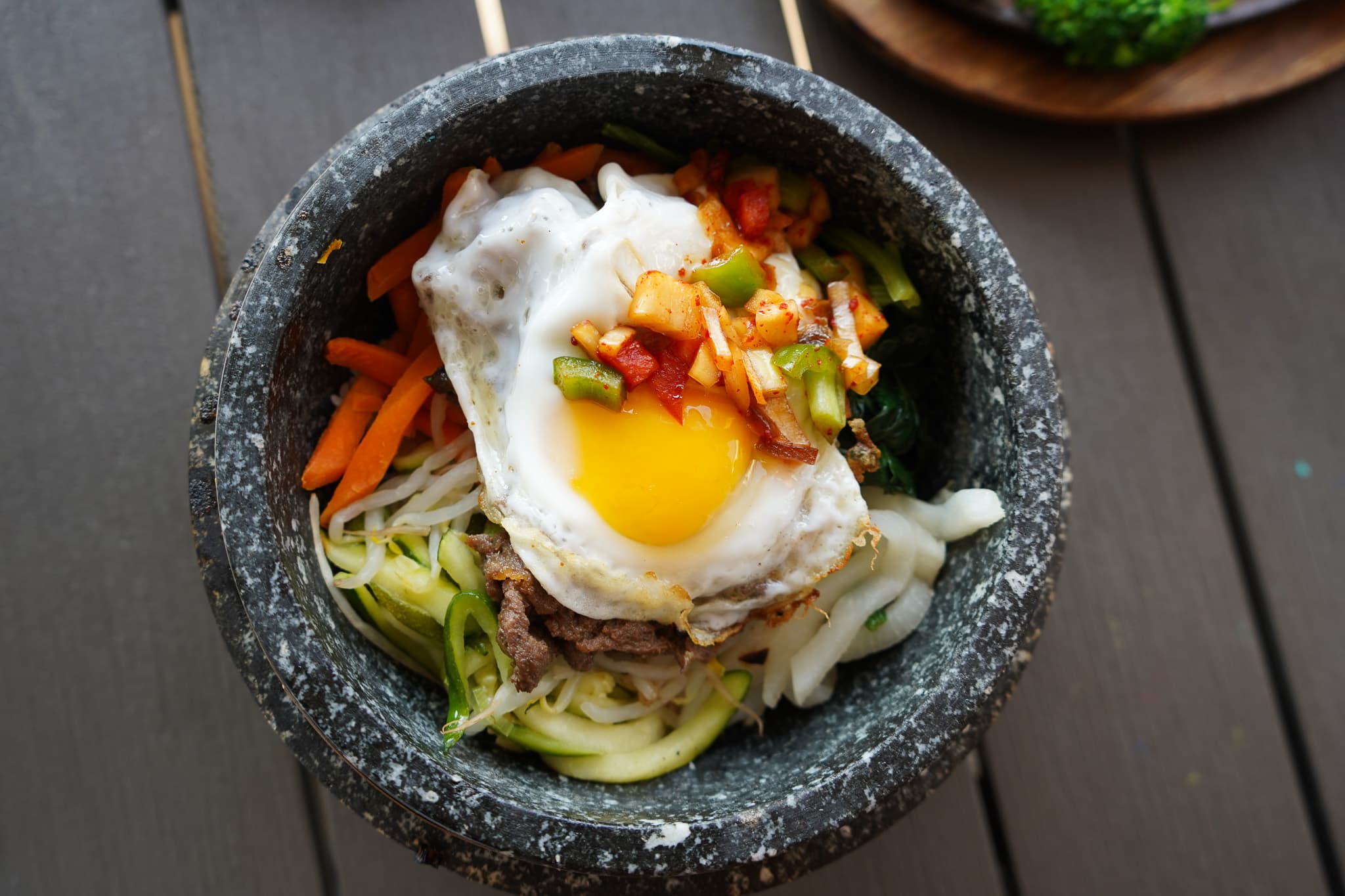 Stone pot bibimbap topped with a fried egg and kimchi